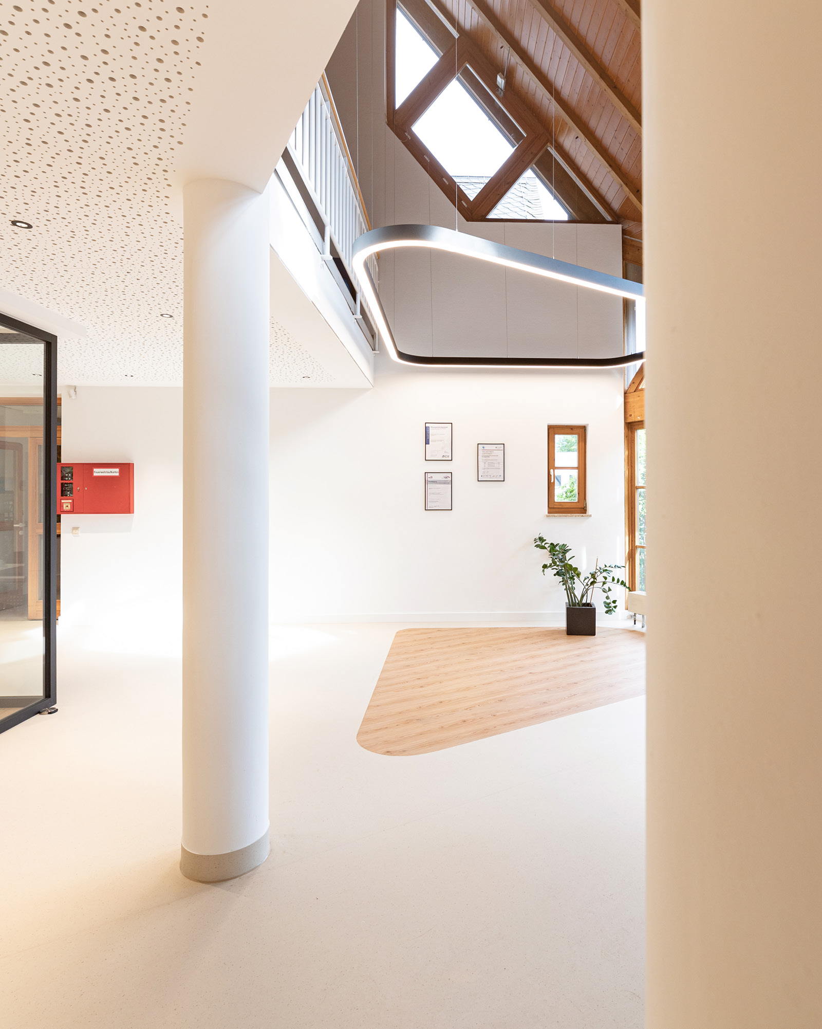 Wartebereich im Eingangsbereich RH Wasser Dörth mit Holzbodenfläche, Akustikdecke und indirekter Beleuchtung