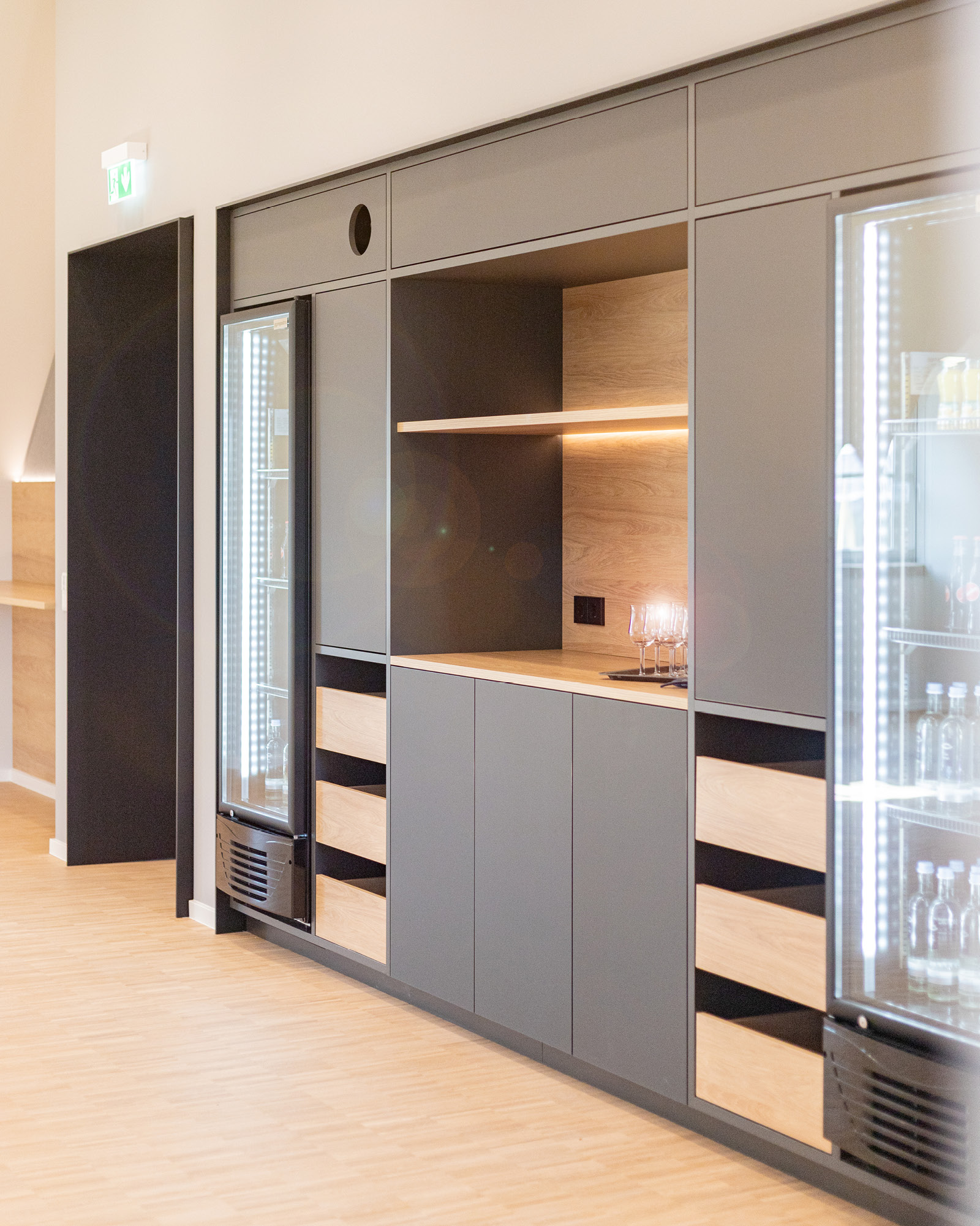 Maßgefertigte Teeküche im Seminarraum Hotel Schloss Montabaur mit integrierten Kühlschränken, Holzdetails und indirekter LED-Beleuchtung