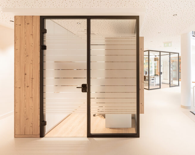 Arbeitsplatz im Eingangsbereich RH Wasser Dörth mit Glasabtrennung, Holzverkleidung und teiltransparenter Folierung